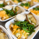 A freshly prepared creamy broccoli chicken dish, topped with cheese and paired with a baked potato and green beans.