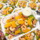 An Asian style shrimp and mandarin salad topped with red onions, carrots and radish with dressing on the side.